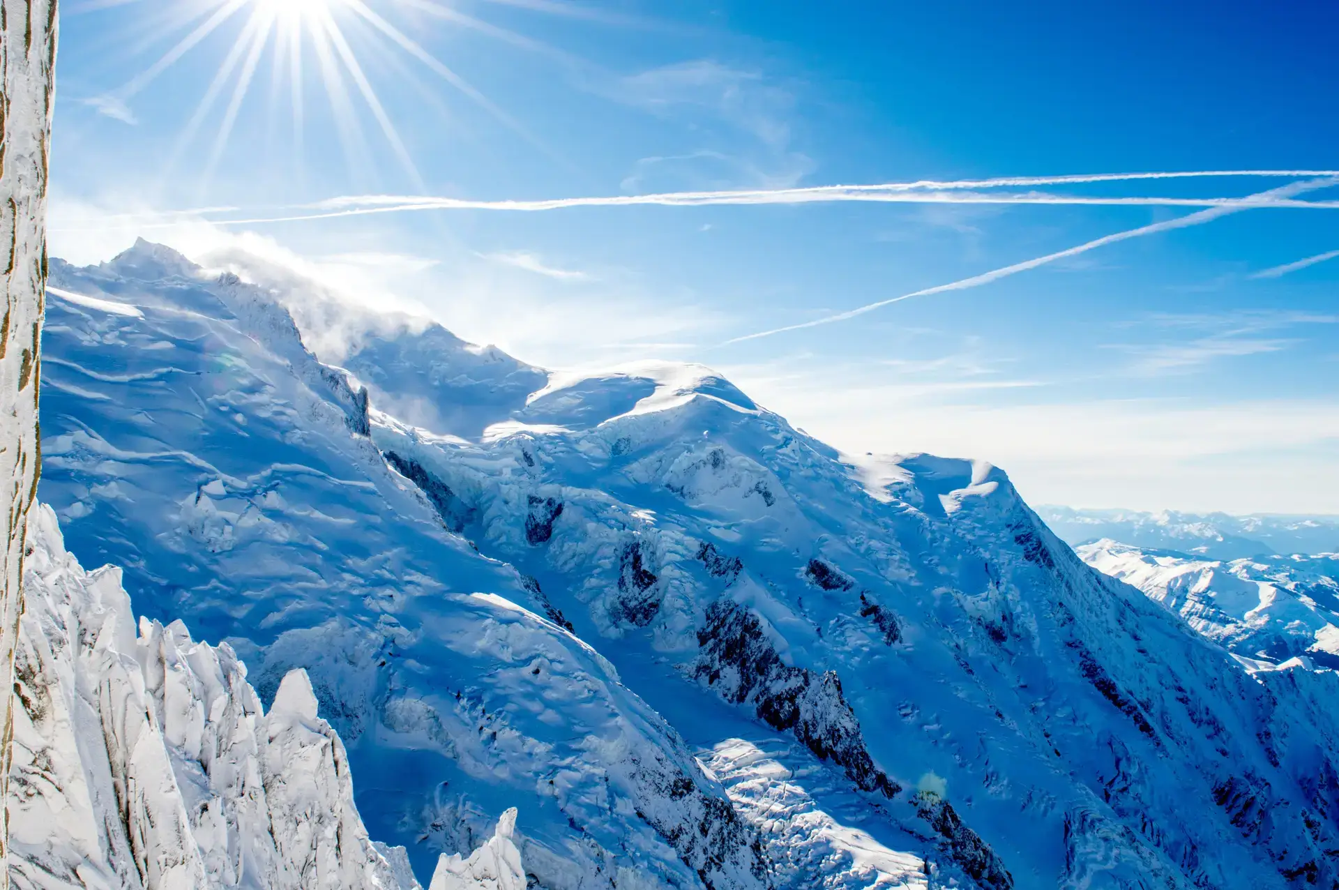 Sunlight over snow-covered mountain ridges beneath a blue sky